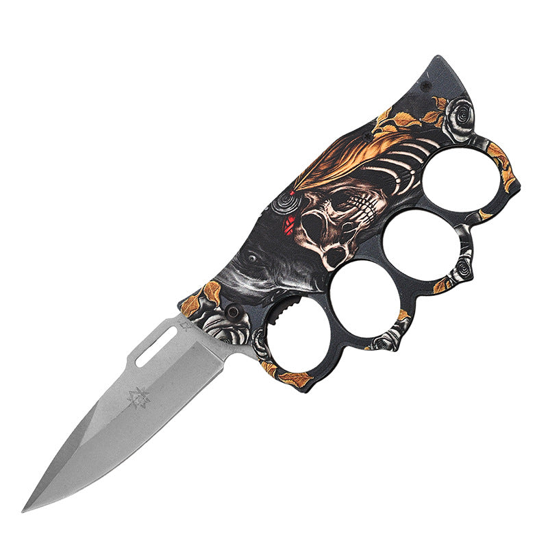 An open knuckle duster folding knife with a wolf, skull, and gold rose graphic handle, displayed on a white background for product clarity.