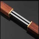 A close-up of a knife with a wooden handle and sheath, featuring brass accents and a silver steel blade visible in the center, displayed on a dark glossy background.