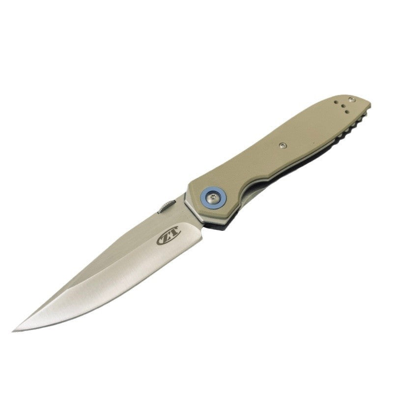 An open Zero Tolerance folding knife with a tan handle, silver blade, and blue pivot screw, displayed on a white background.