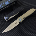 A closed black Zero Tolerance knife and an open tan Zero Tolerance knife, displayed on a dark textured surface with a box and pouch in the background.