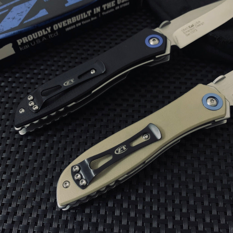 A view of the back side of two Zero Tolerance folding knives, showcasing the black pocket clips on both the black and tan handles.